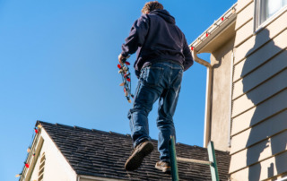 Worker Hanging Christmas Lights on Roof