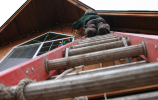 Worker Climbing Ladder on House